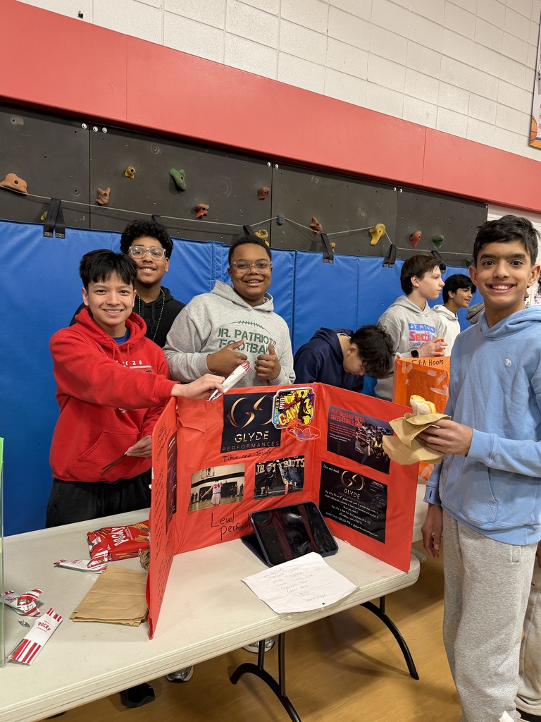 4 boys standing at a table with a project from the business fair.
