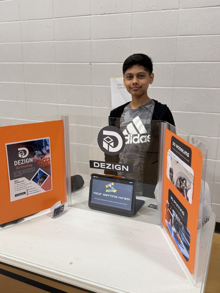 Student standing behind a table with his project at a business fair.
