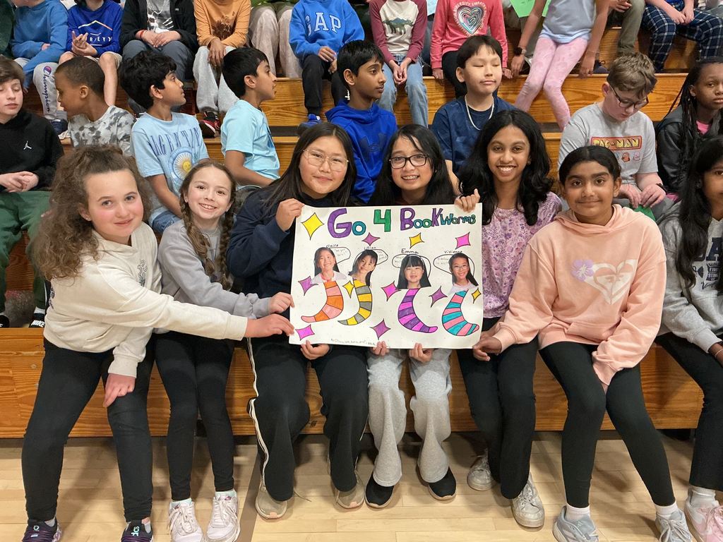 STudents sitting together with a handmade sign cheering for their team.
