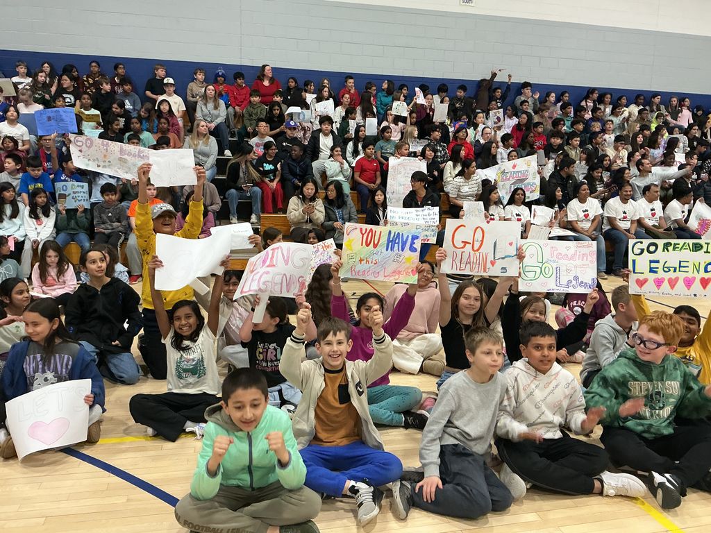 STudents holding up signs in the bleachers cheering for their teams.
