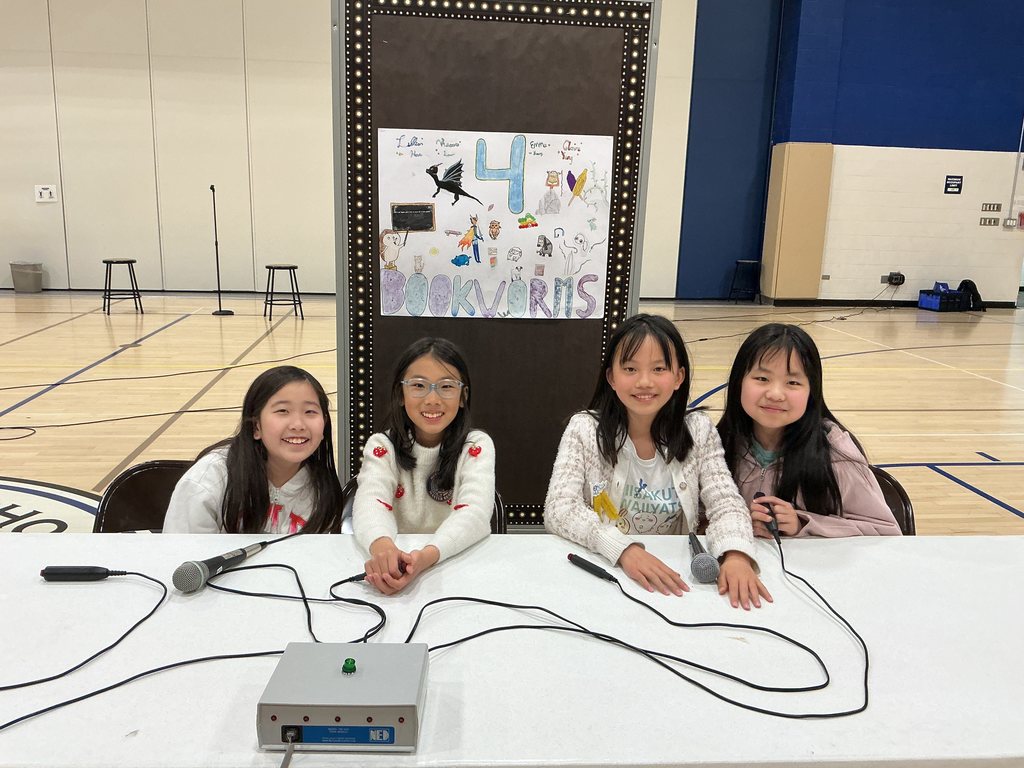 The team, 4 Bookworms are sitting at a table with their buzzers.