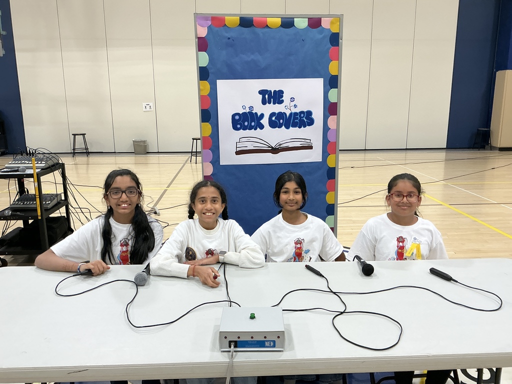 The book clovers, winner of the contest, sitting at a table in front of their team sign.