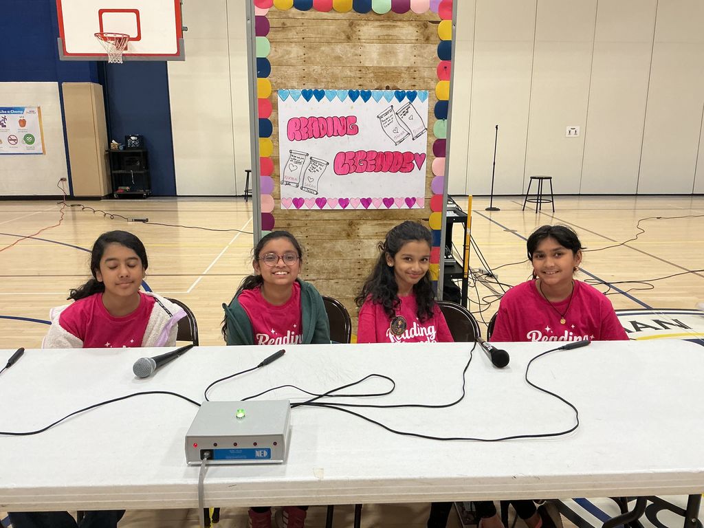 Reading Legacy Team sitting at a table with their team name behind them.