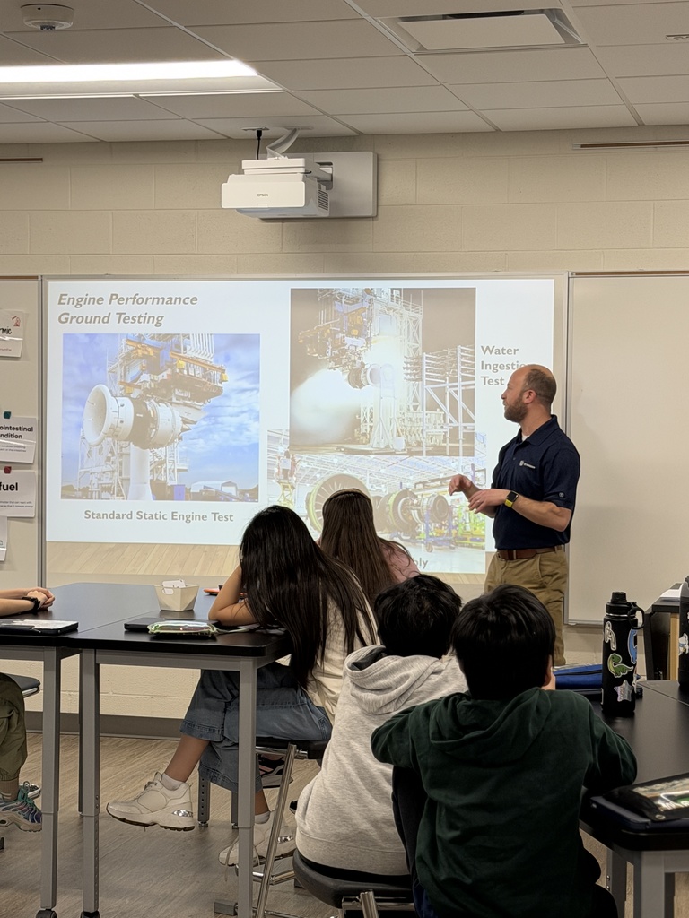 Presenter showing photos of engines as he teaches about what he makes.