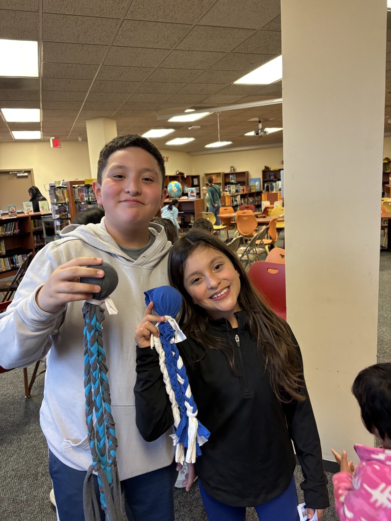 Two students standing and holding their dog toys.