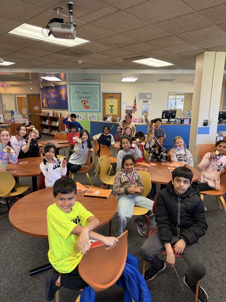 Group of students sitting at a desk with their awards.