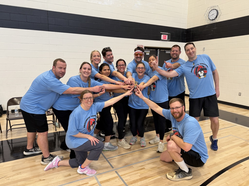 Staff standing with their hands on a little trophy.