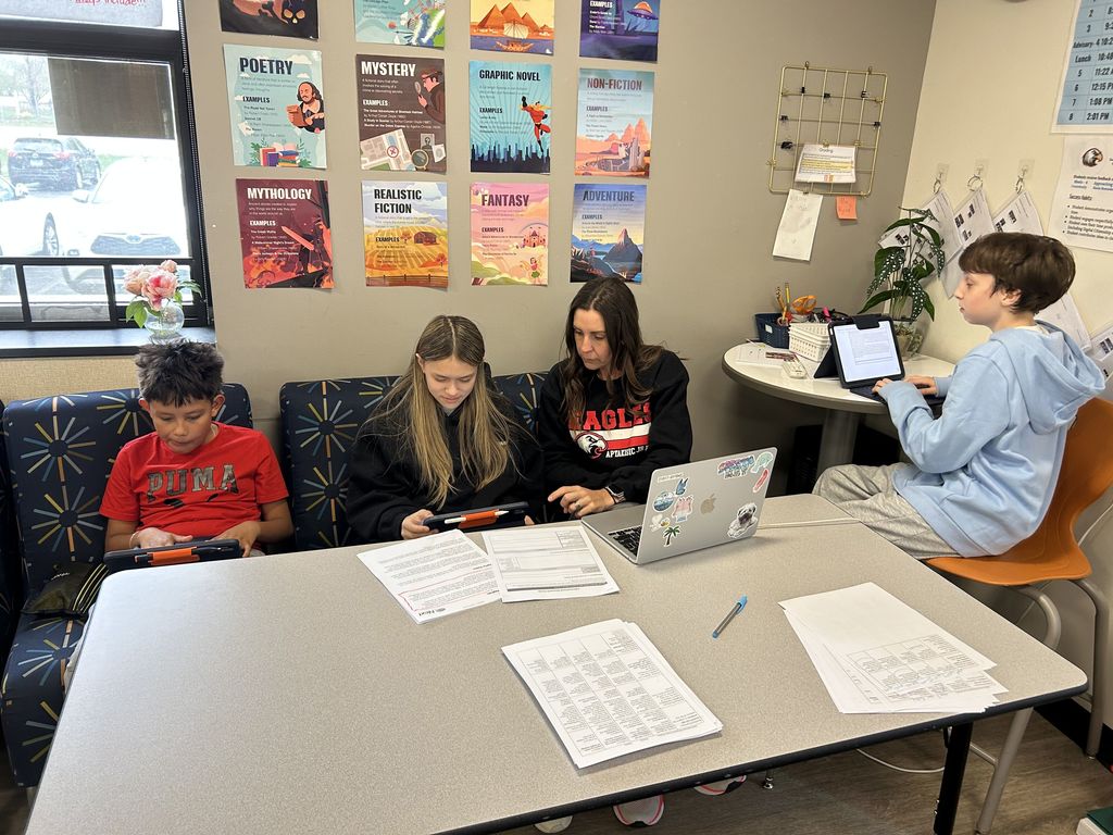 Students sitting next to a teacher while they work.