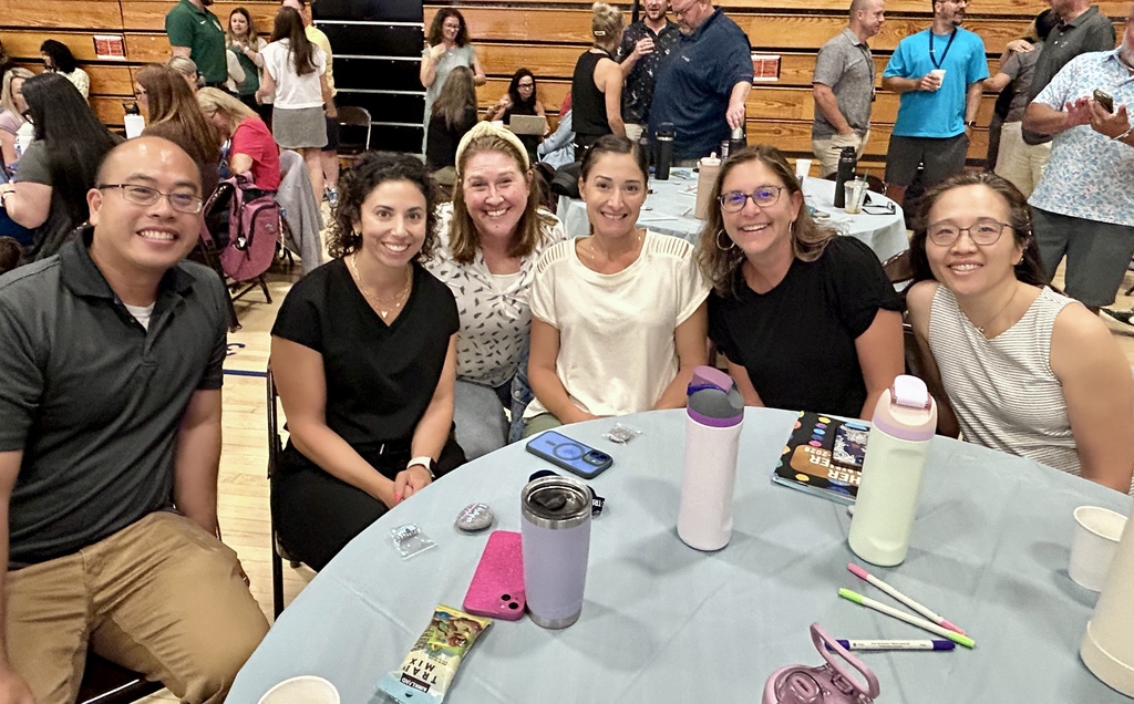 Teachers sitting at a table smiling.
