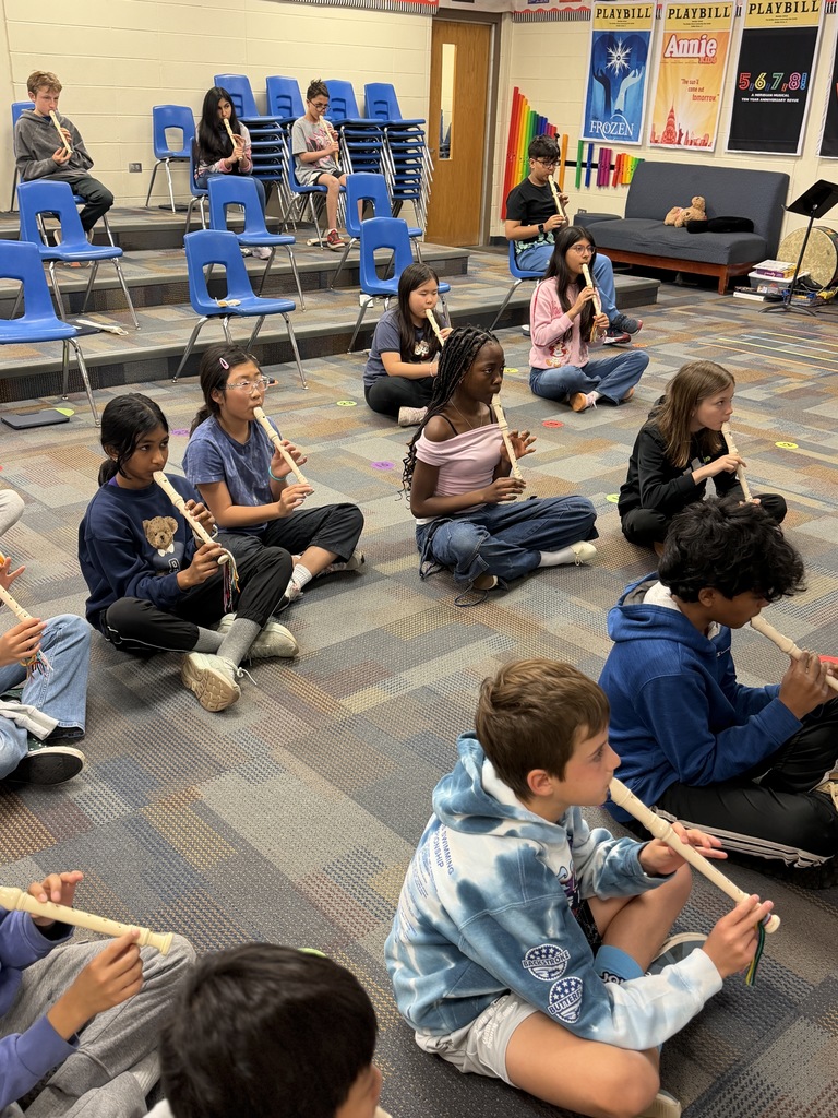 Students sitting on the floor playing the recorder. 