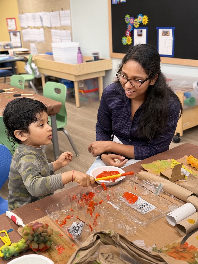 Mother and son sitting at a table with paint and recycled materials.