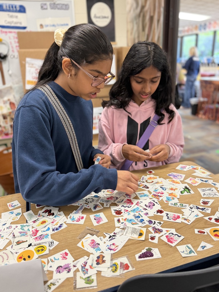 Students choosing tattoos from a table.