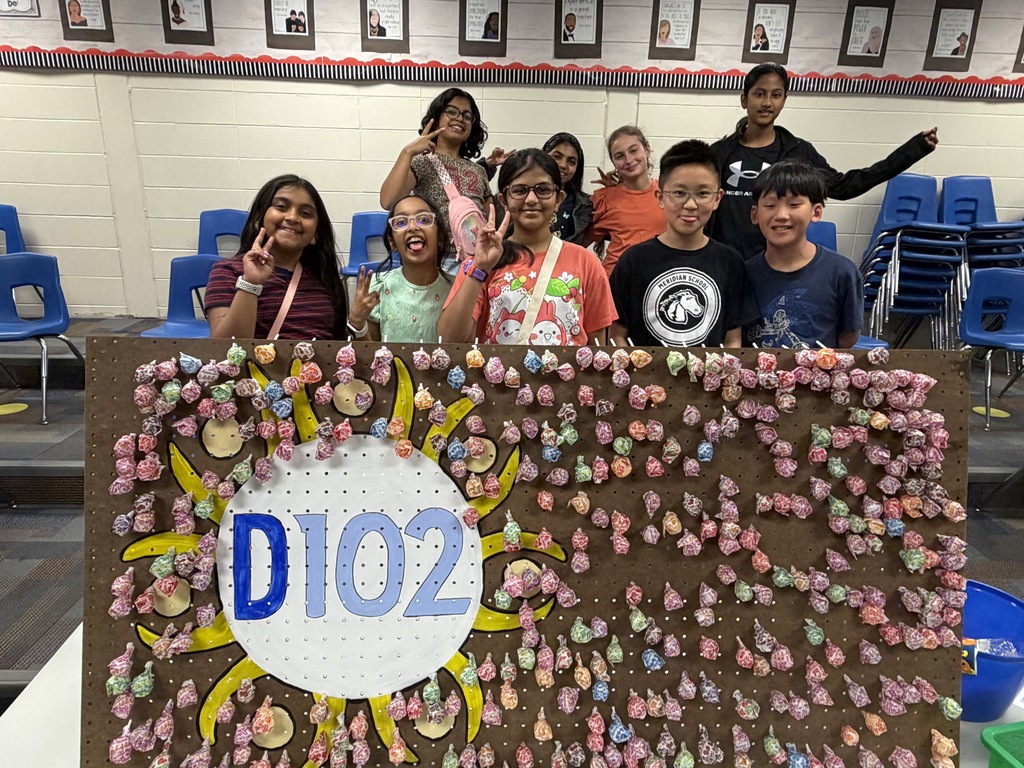 Students standing around a D102 sign with loli-pops.