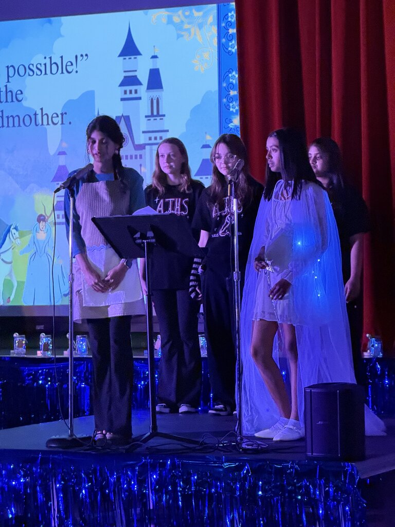Students in costume on stage talking into a mic.
