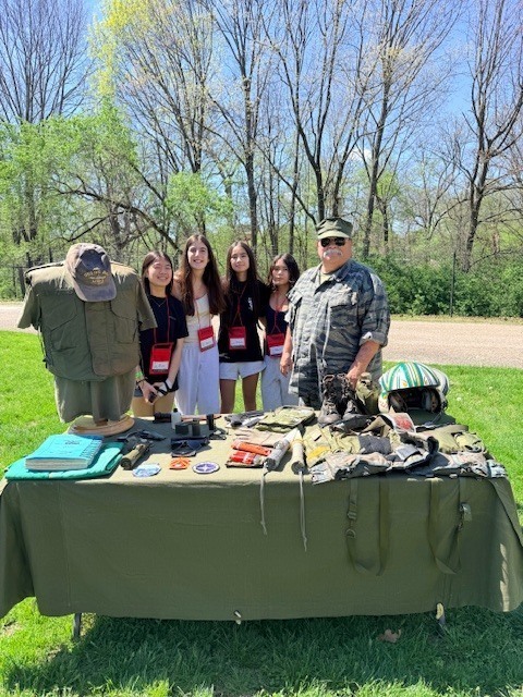 Students standing by military equipment.