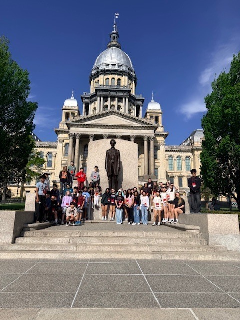 STudents standing in front of monument.