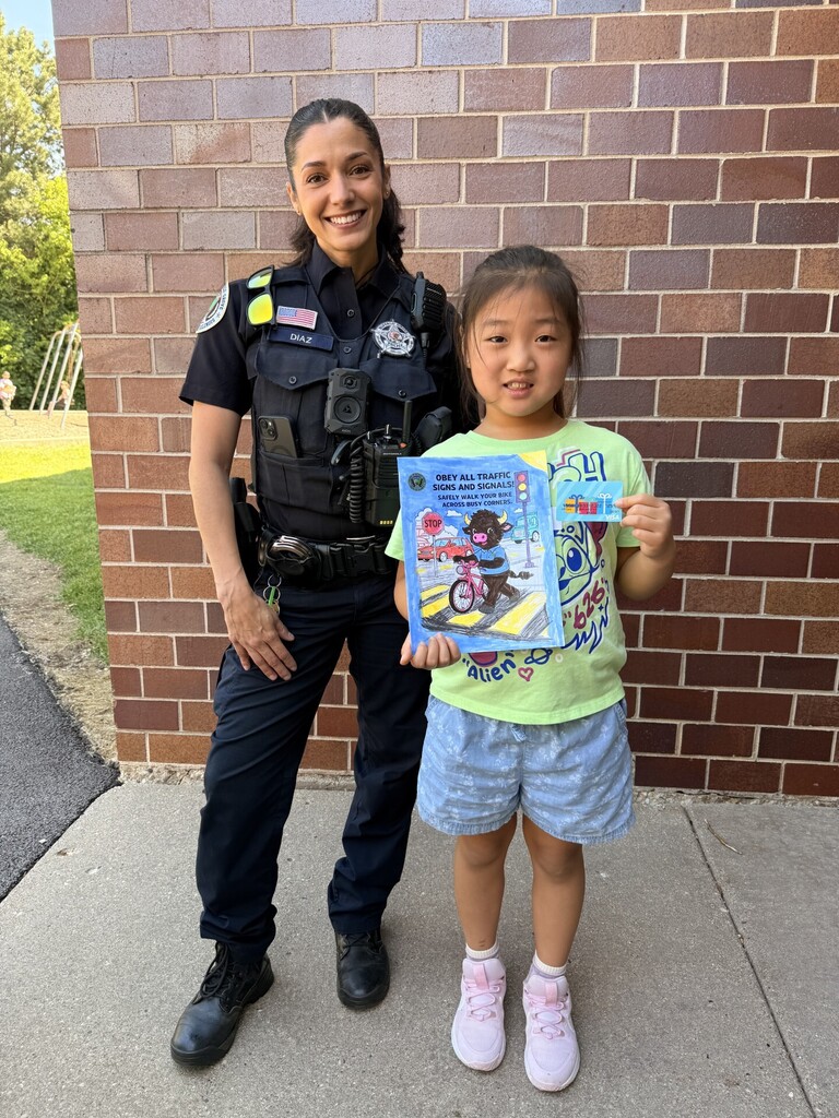 Student standing with Officer Diaz and her coloring page.