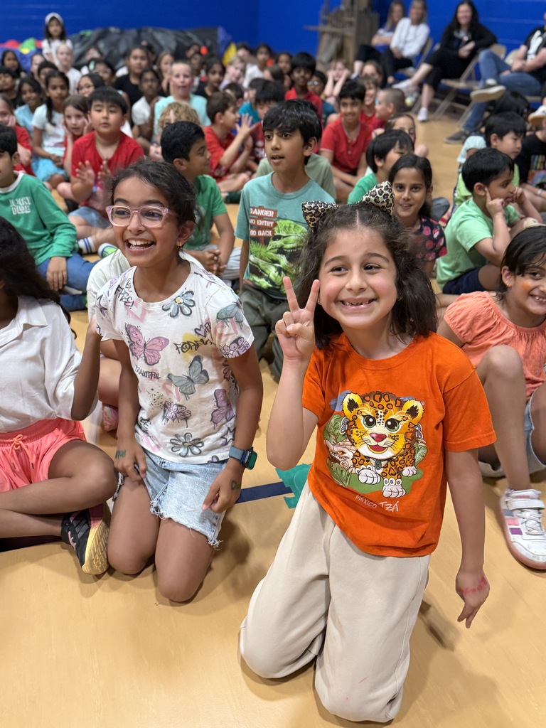 Students smiling at an assembly.