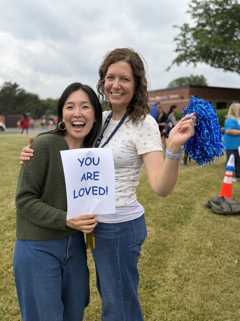 Teachers smiling and holding a sign.