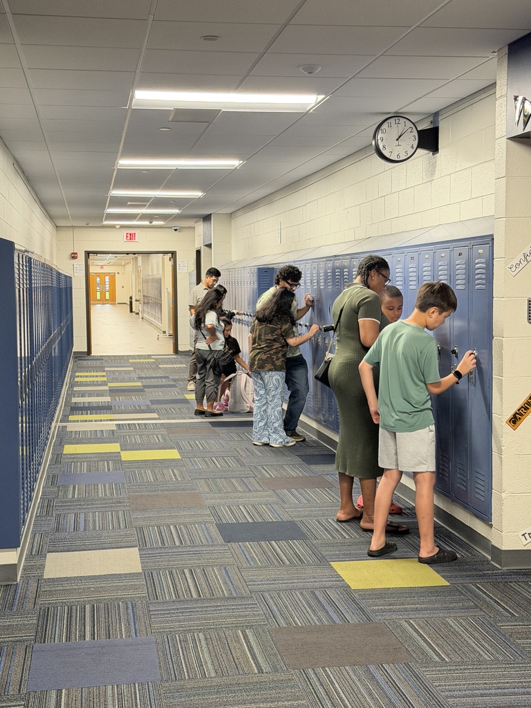 Students and parents standing at a locker working on their codes. 