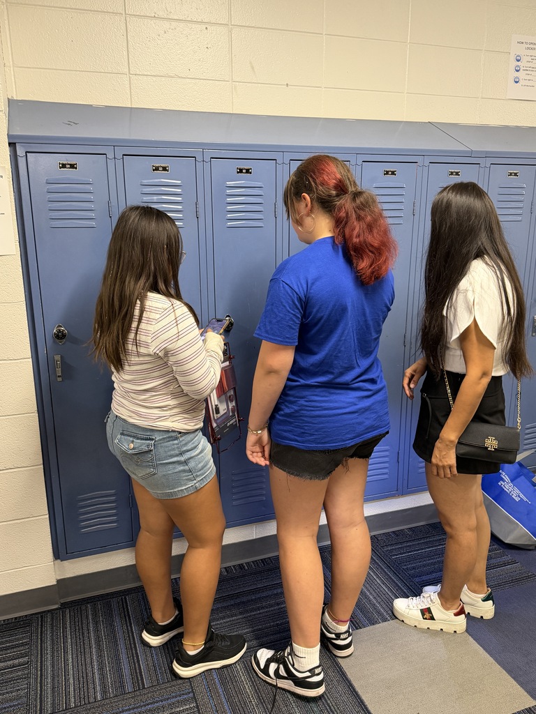 STudents standing at a locker. 