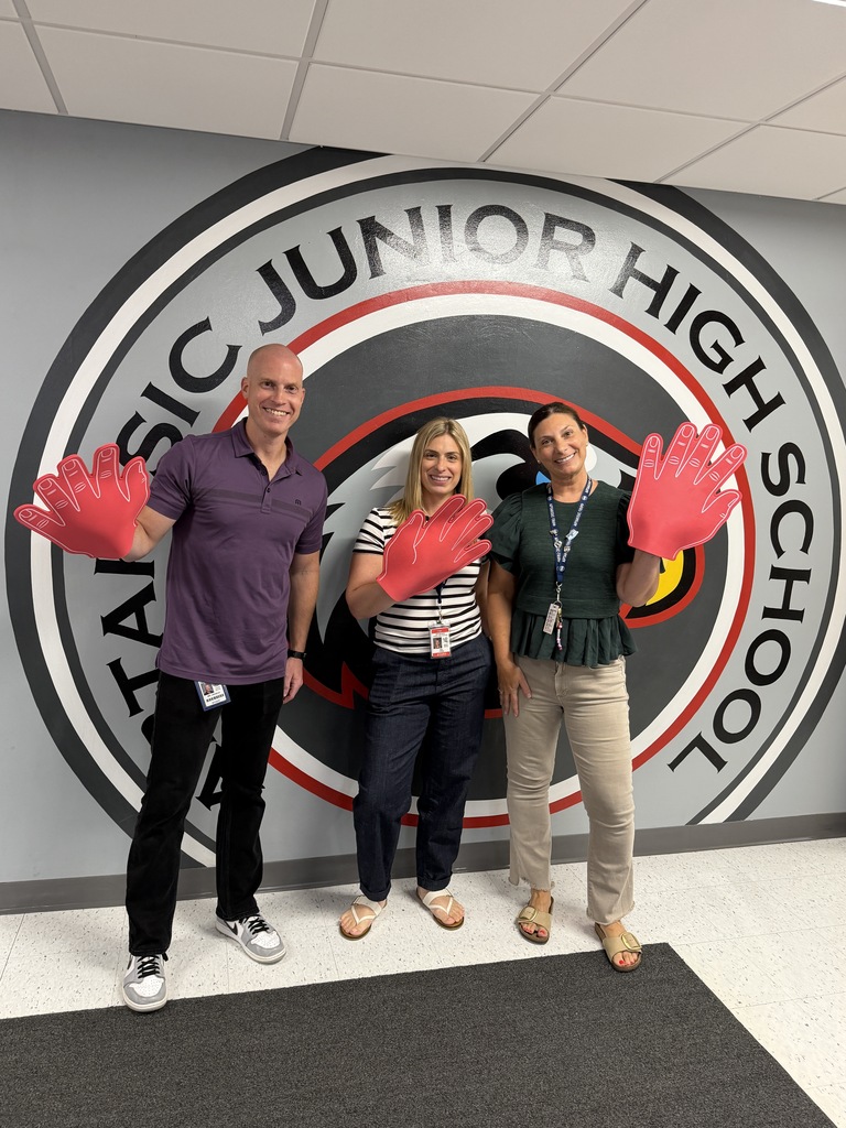 Principals standing in front of the logo with their foam hand.