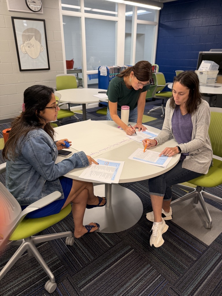 3 teachers sitting at a table working. 
