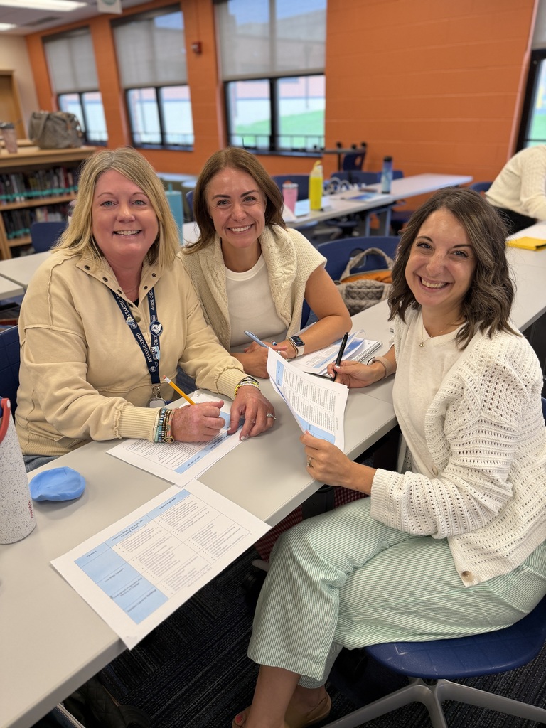 3 teachers sitting at a table reviewing data. 