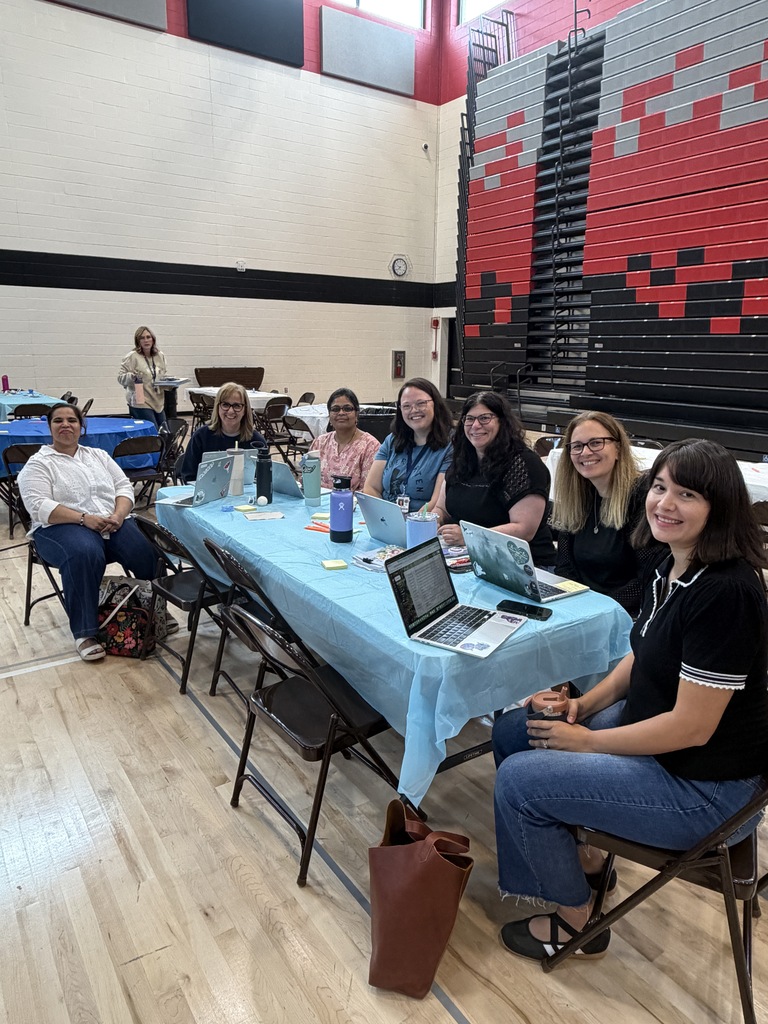 Teachers sitting at a table listening. 