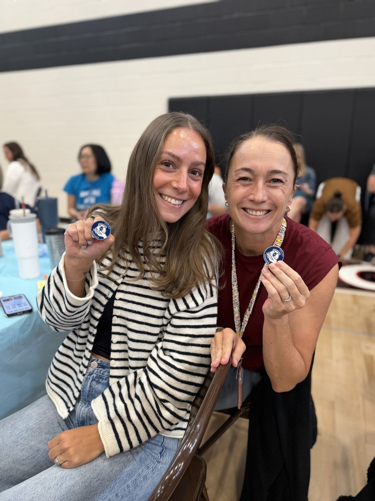 2 teachers holding their commitment pins.