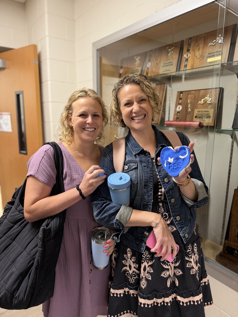 2 teachers holding clay and smiling. 