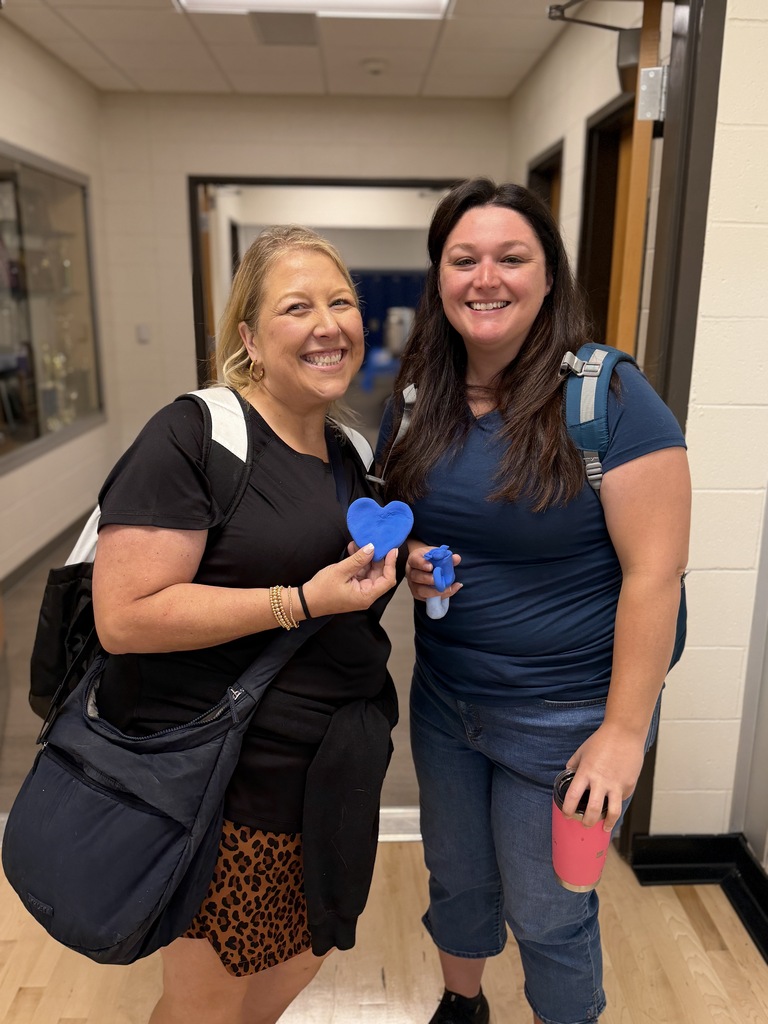 2 teachers holding their clay creations.