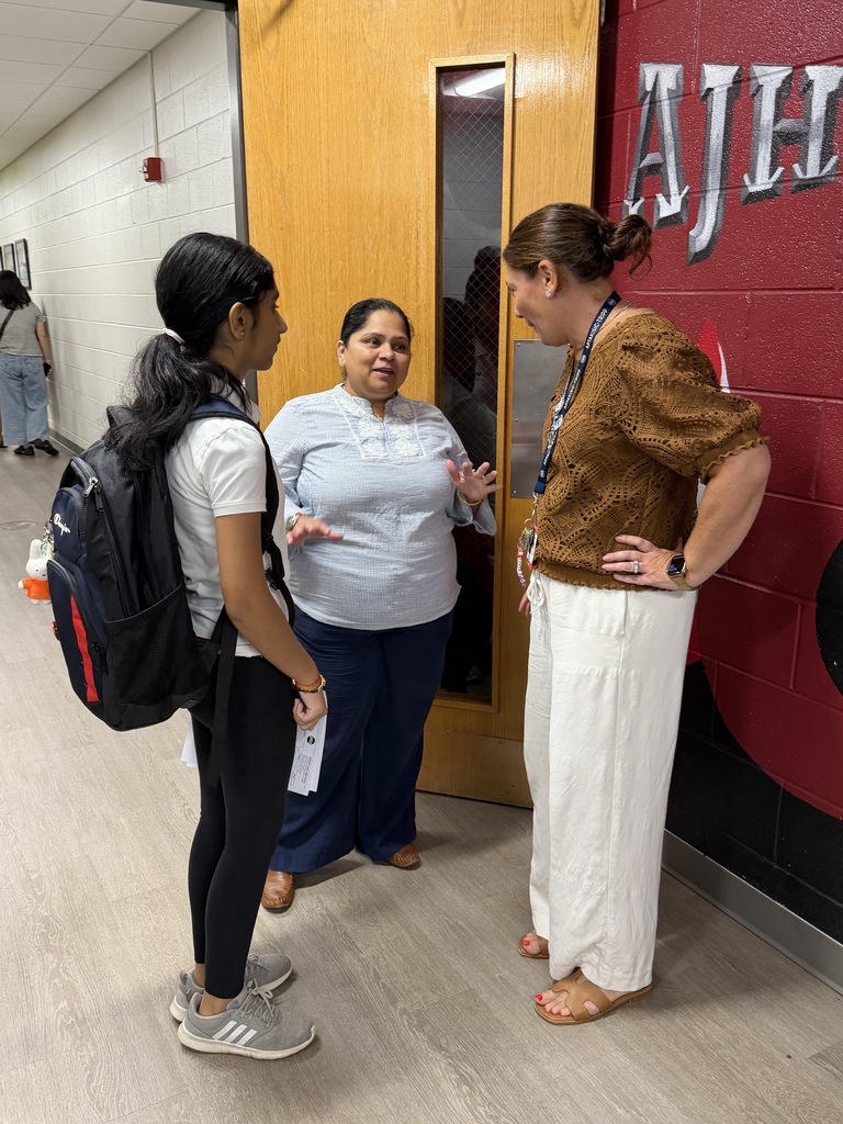 Principal Tamez meets with 2 people standing in the hall.