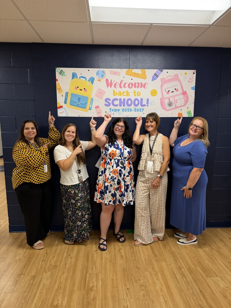 Teachers pointing to the back to school sign.