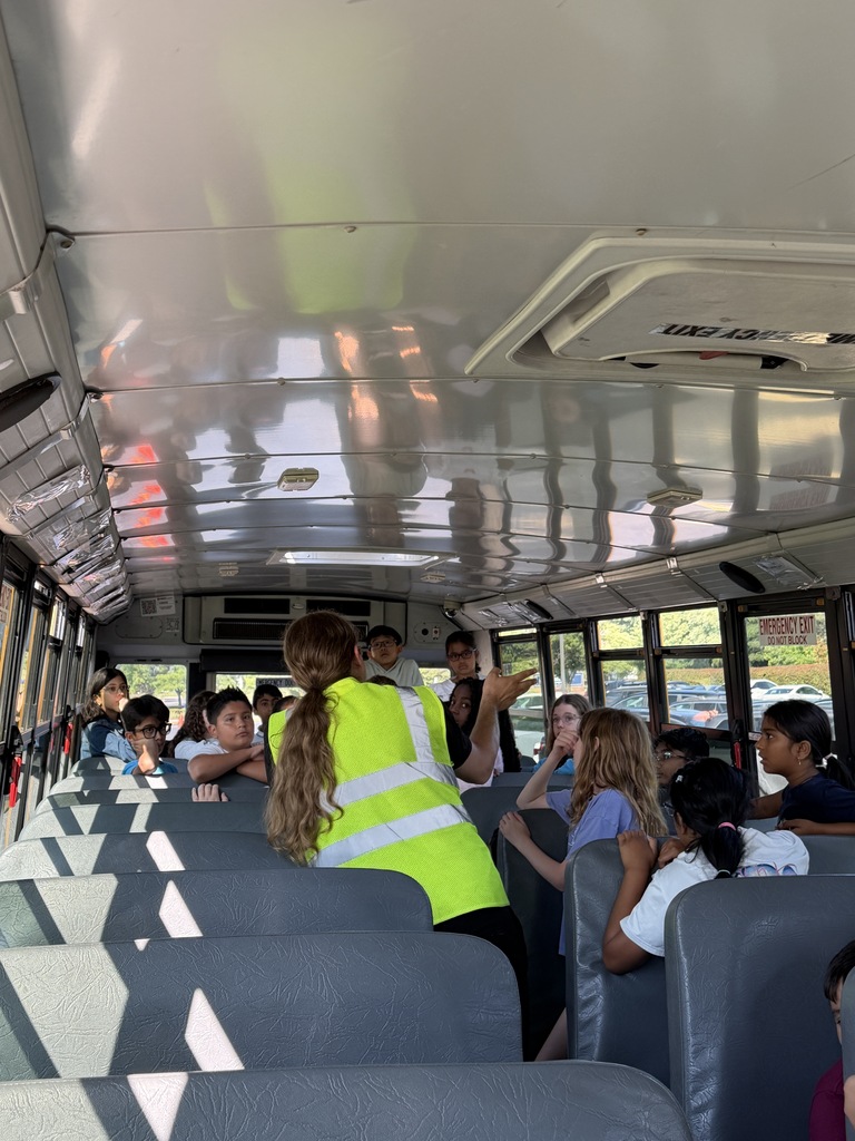 Students on the bus with the driver listening to safety tips.