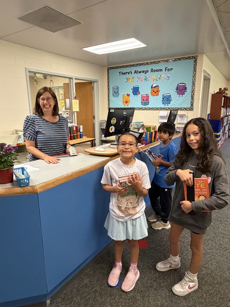 Librarian standing with students at her desk.