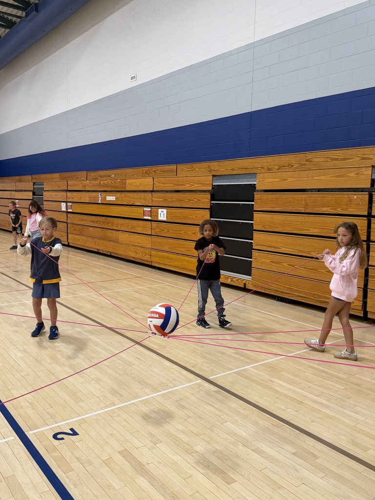 Students holding the string and placing the ball on top of the cone.