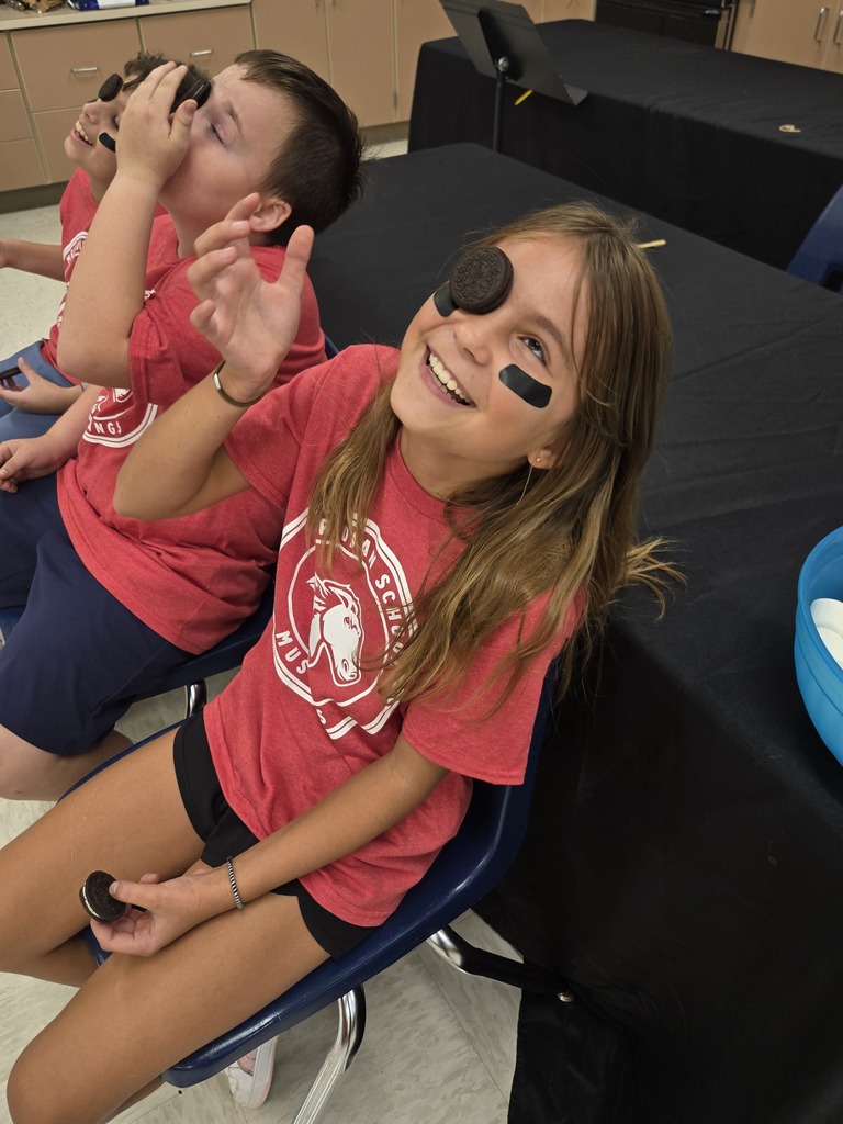 Students sitting and smiling with an oreo cookie on their face.