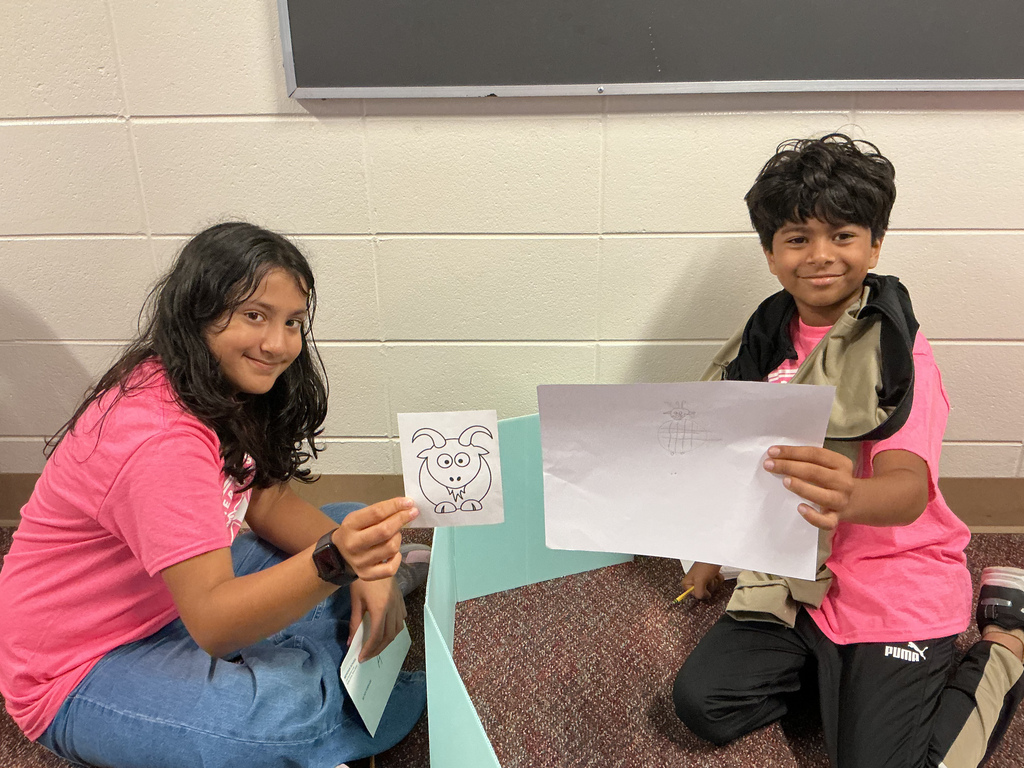 Students sitting on the floor with artwork.