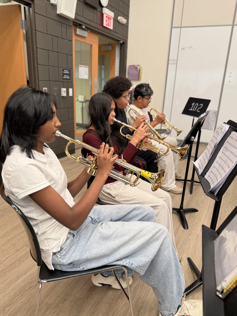 Students sitting down and playing music.