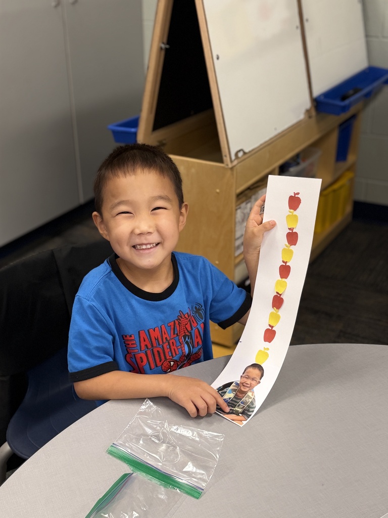 Little boy holding up his craft. smiling.