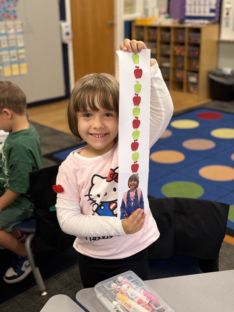 Little girl holds up craft smiling.