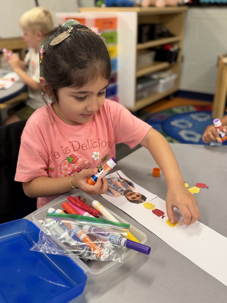 Little girl sitting at her table with a craft, smiling.