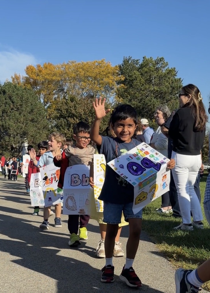 Students walking outside with their letter posters.
