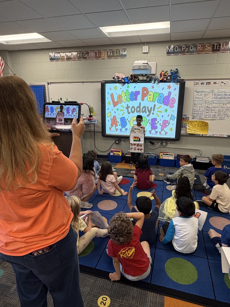 teacher taking a photo of a student with his letter poster.