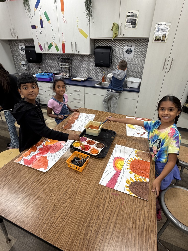 3 students working at a table, painting.