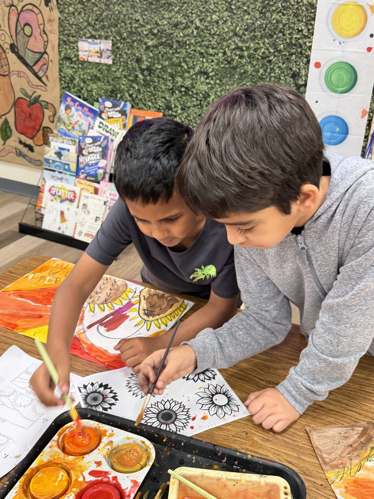2 boys reaching over to paint.