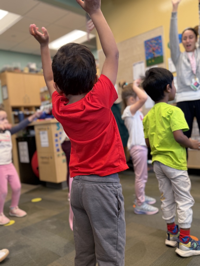 Student in red shirt has arms in the air.