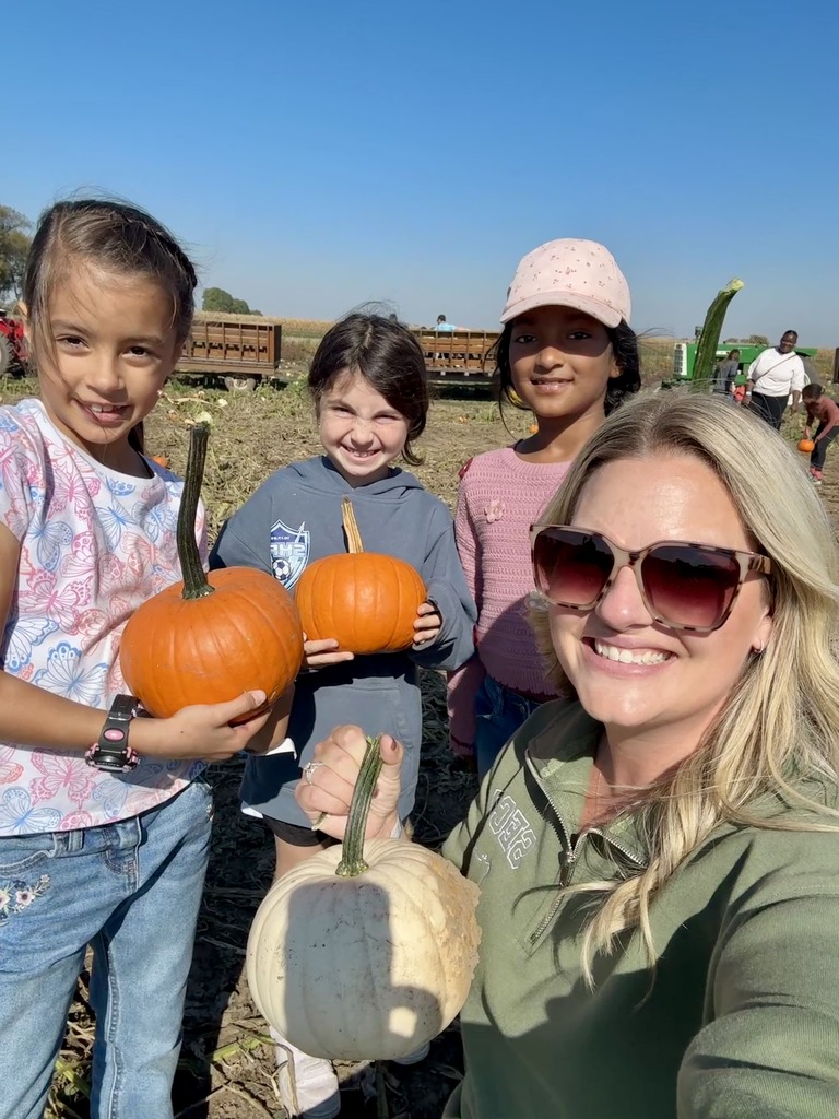 Mrs. K. taking a selfie with 3 girls holding pumpkins.