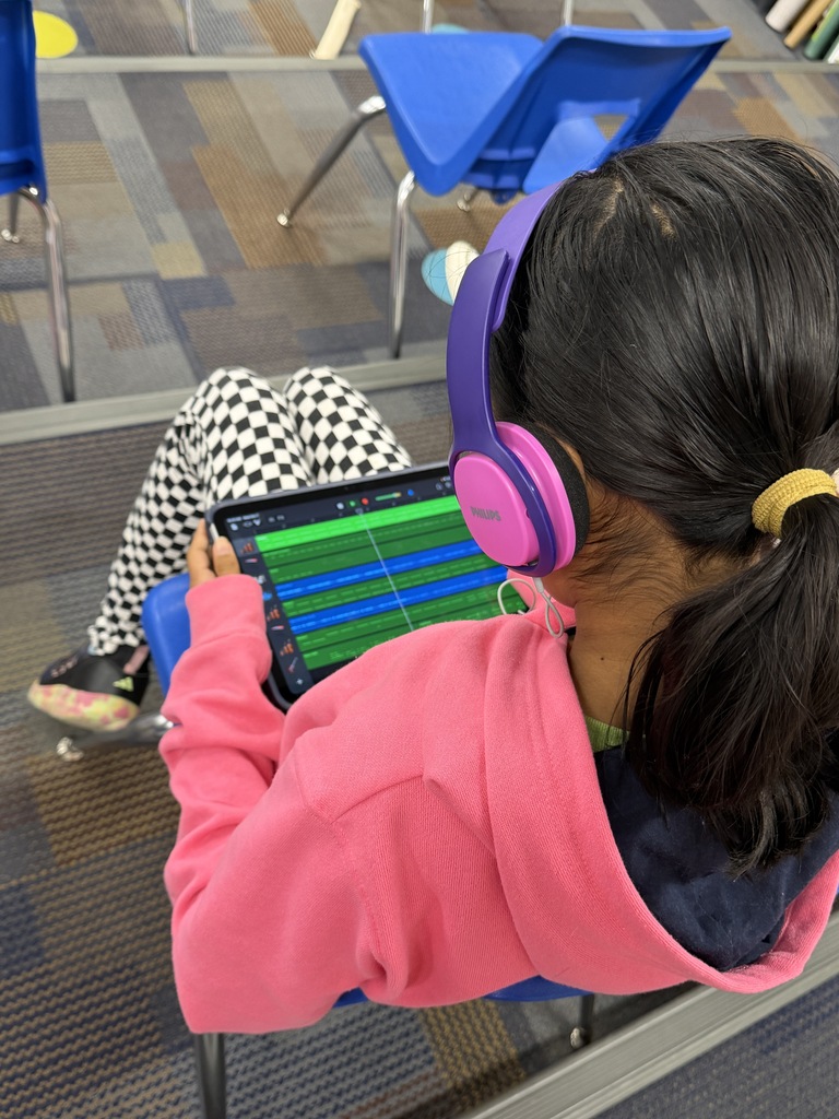 student holding ipad with headphones.